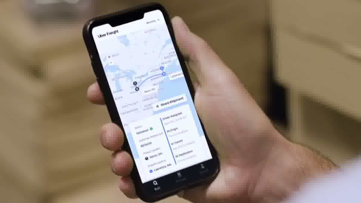 Uber Freight mobile app showing a shipment route map from Akron, OH to Lawrence, MA with Delivered status, customer reference number, and a Driver Assigned to At Destination milestone timeline